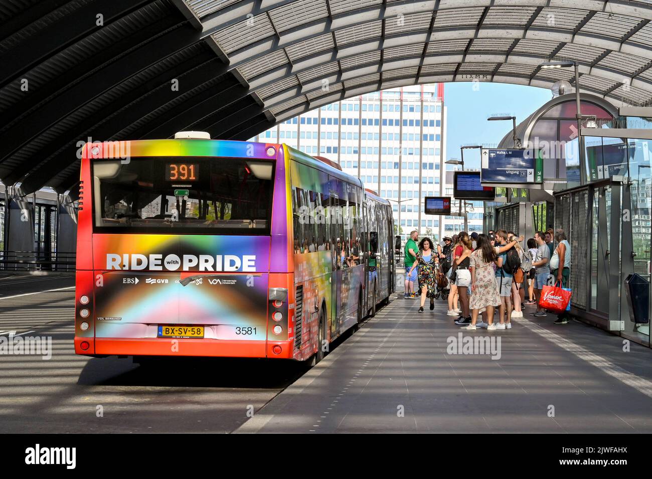 Amsterdam, Niederlande - August 2022: Menschen warten darauf, unter dem geschwungenen Dach des Amsterdamer Bahnhofs Centraale in einen öffentlichen Bus zu steigen Stockfoto