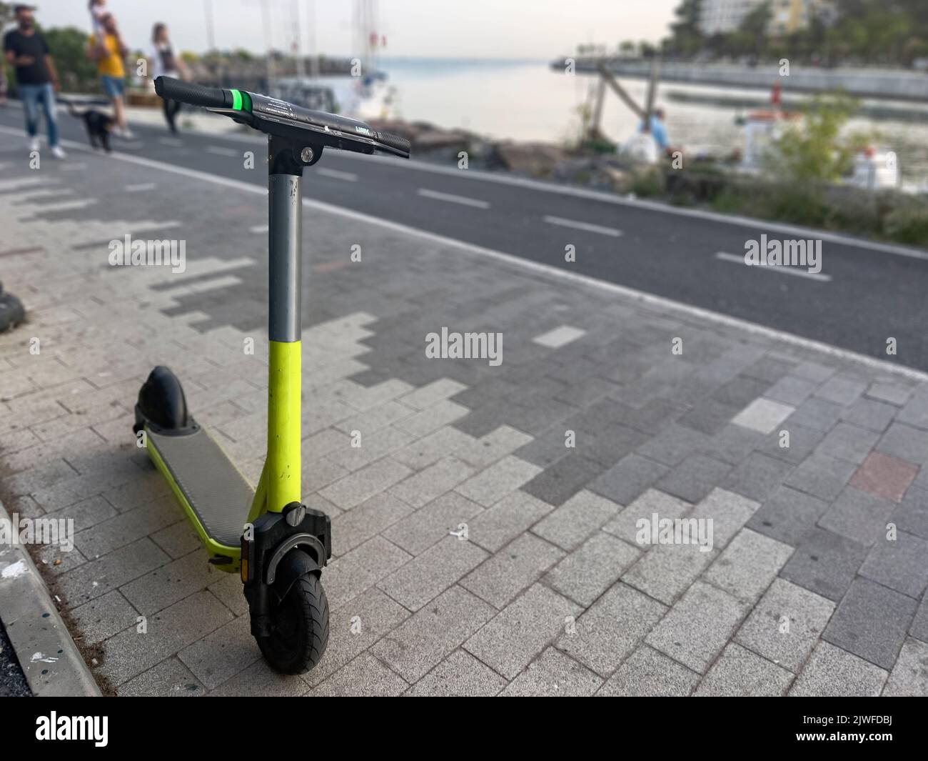 Moderner E-Scooter, der an sonnigen Tagen in der Fahrradspur geparkt ist, „zu mieten“. Abgebrochener Transport. Ökologischer nachhaltiger Verkehrsanteil Stockfoto