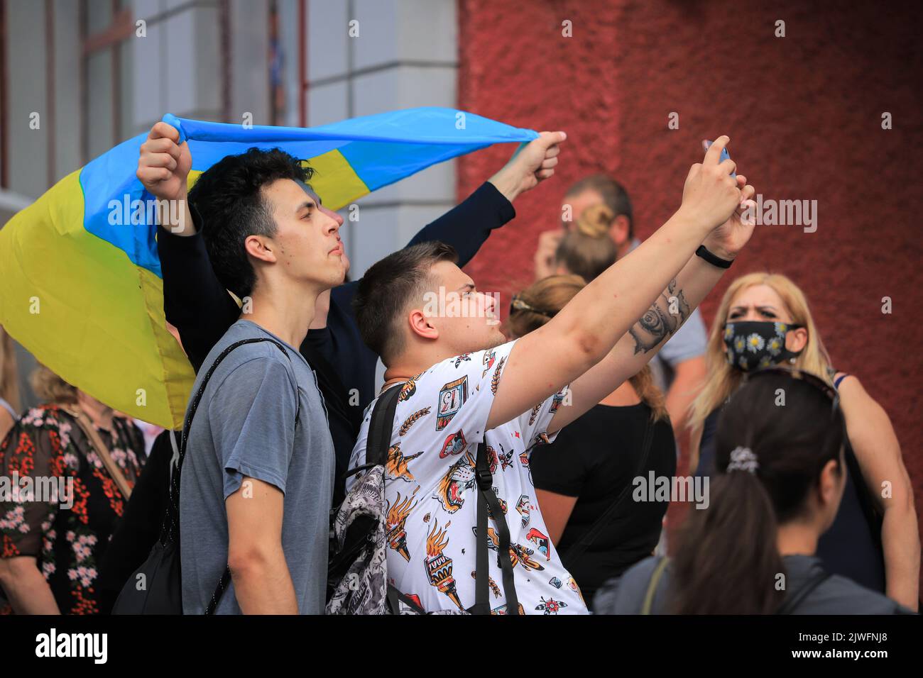 Kiew, Ukraine - 24. august 2021: Junge Männer werden am Unabhängigkeitstag der Ukraine unter der Flagge der Ukraine fotografiert Stockfoto
