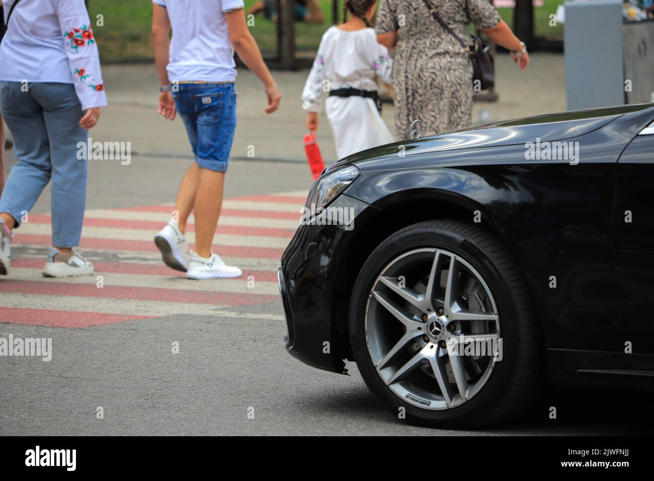 Auto Mercedes-Benz passiert Menschen auf einer Fußgängerüberfahrt Stockfoto