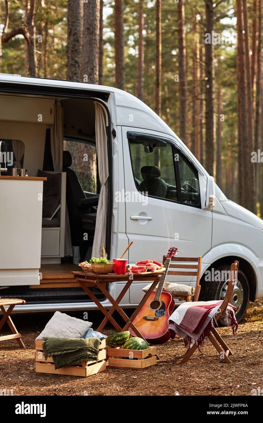 Vertikales Bild des Tisches mit Essen auf Picknick in der Natur mit Haus der Räder im Hintergrund Stockfoto