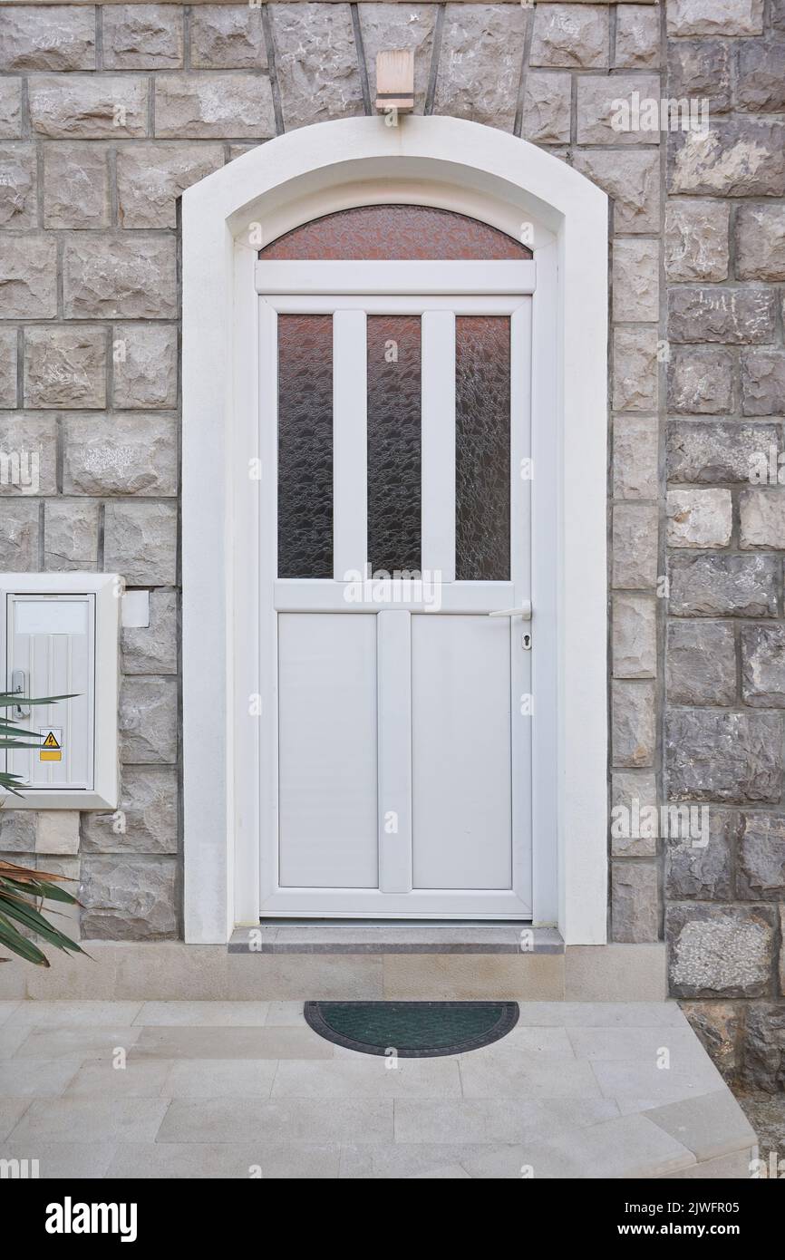 Weiße Kunststoff-Haustür mit Glas an der Fassade des Hauses Stockfoto