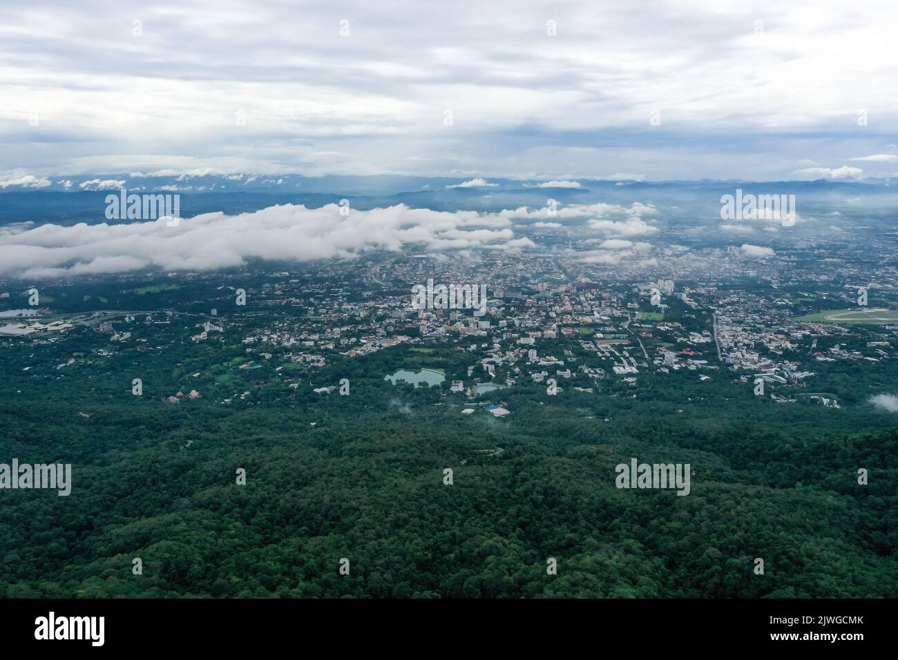Blick von oben auf den Berg in Chiang Mai City, Thailand. Weiße Wolken und Staub sind über dem Berg, während Städte weit entfernt zu sehen sind. Stockfoto
