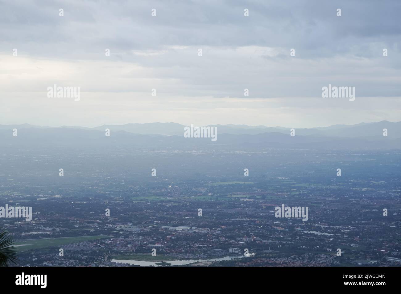 Blick von oben auf den Berg in Chiang Mai City, Thailand. Weiße Wolken und Staub sind über dem Berg, während Städte weit entfernt zu sehen sind. Stockfoto