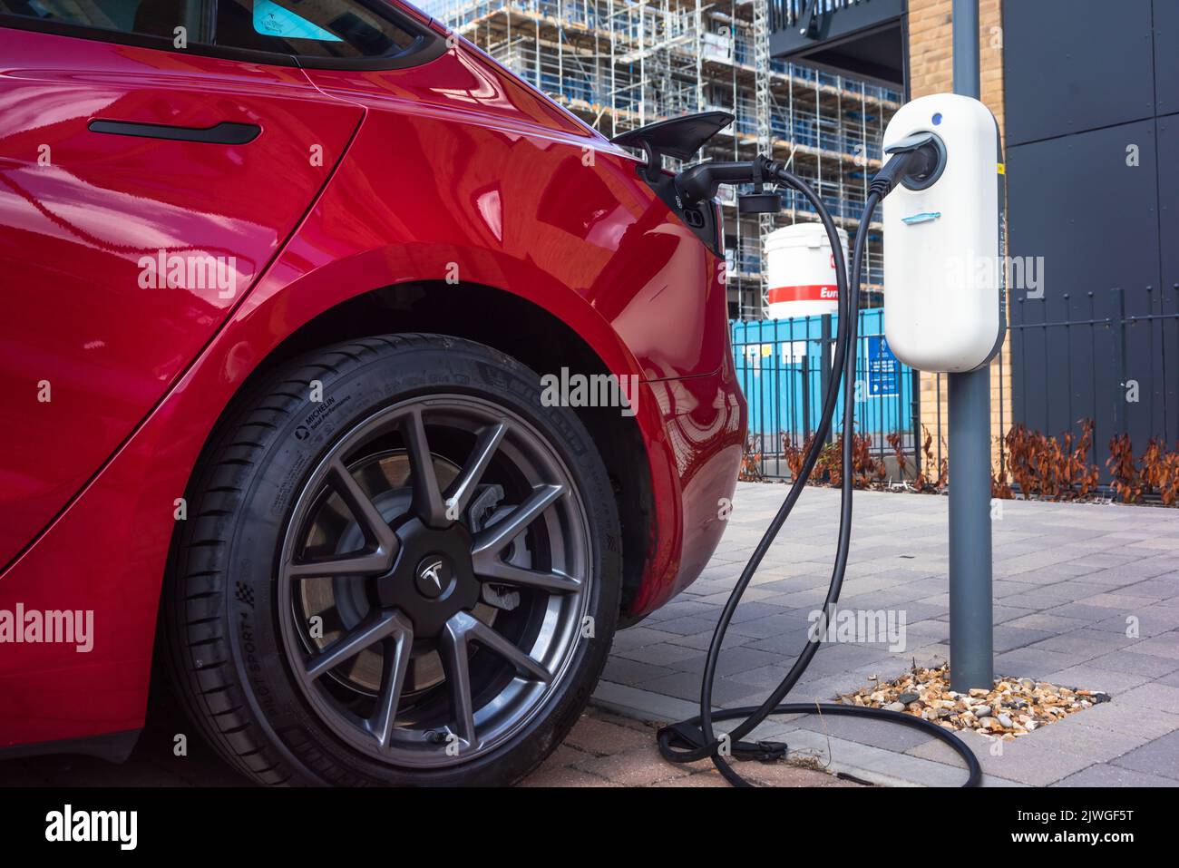 Ein rotes Tesla-Auto lädt seine Autobatterie an einer Ladestation für Elektrofahrzeuge in Southampton, England, Großbritannien Stockfoto