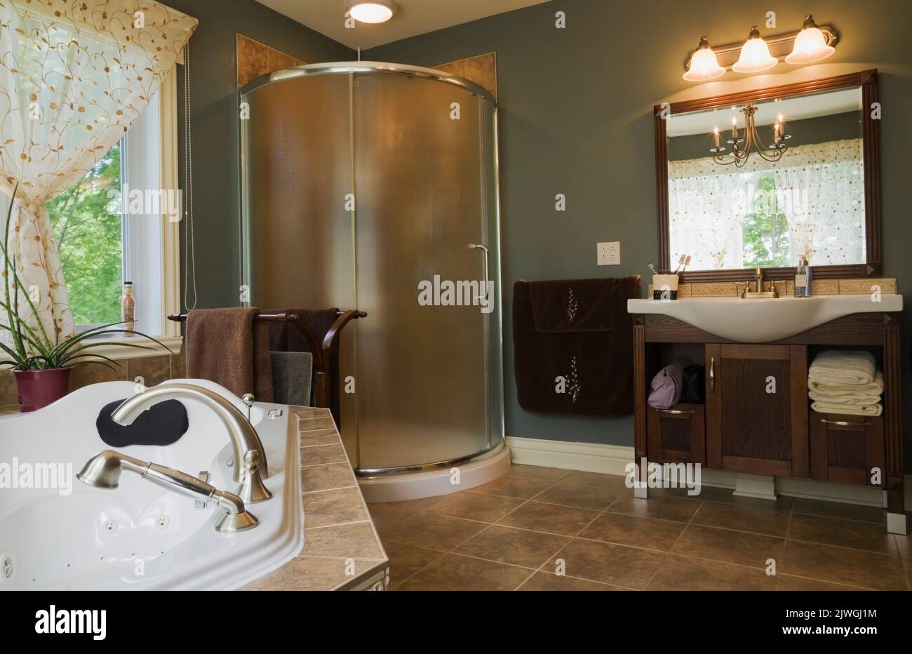 Hauptbadezimmer mit Whirlpool-Badewanne, Glasduschkabine und Waschbecken aus Porzellan im modernen Haus im Landhausstil. Stockfoto