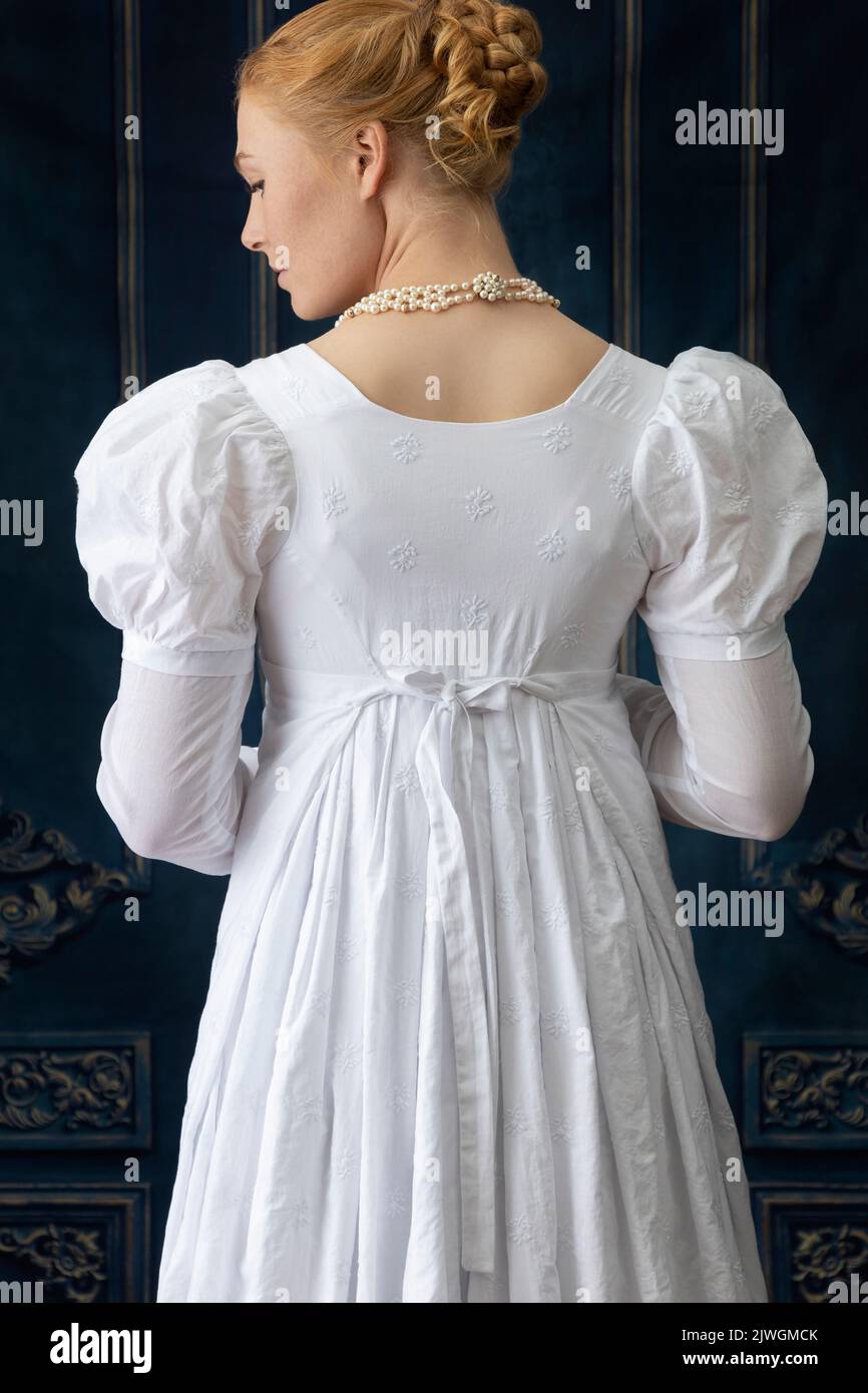 Eine Regency-Frau, die ein weißes, besticktes Musselin-Kleid mit Perlenkette trägt Stockfoto
