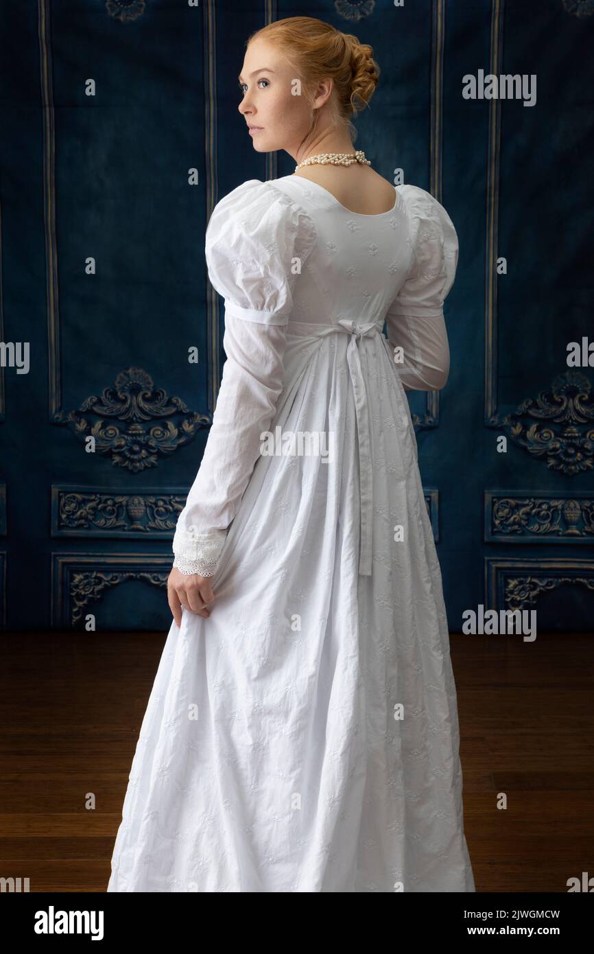 Eine Regency-Frau, die ein weißes, besticktes Musselin-Kleid mit Perlenkette trägt Stockfoto
