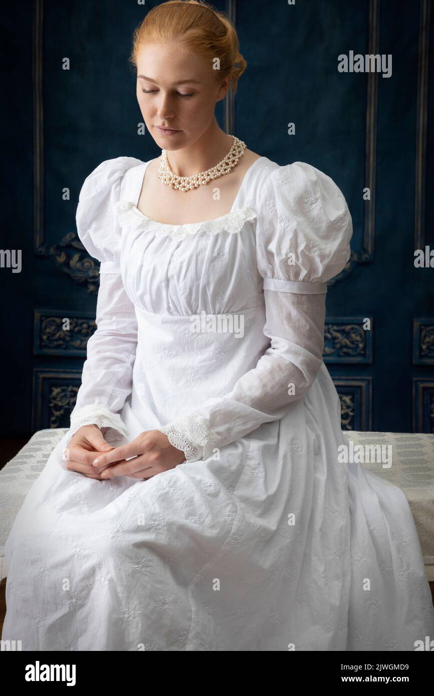 Eine Regency-Frau, die ein weißes, besticktes Musselin-Kleid mit Perlenkette trägt Stockfoto