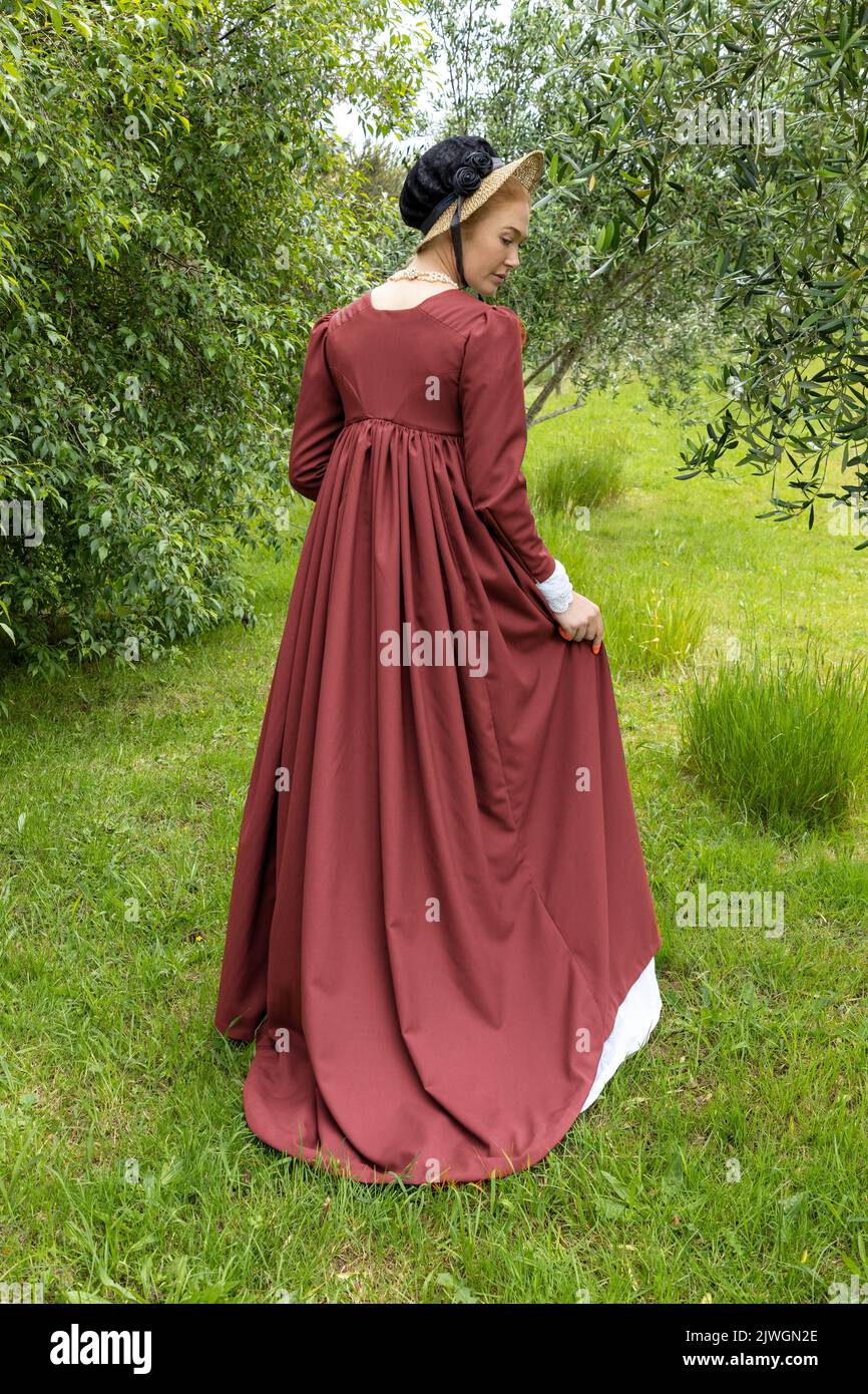 Eine Regency-Frau, die ein weißes, besticktes Musselin-Kleid mit einem langen spencer über der Oberseite trägt Stockfoto