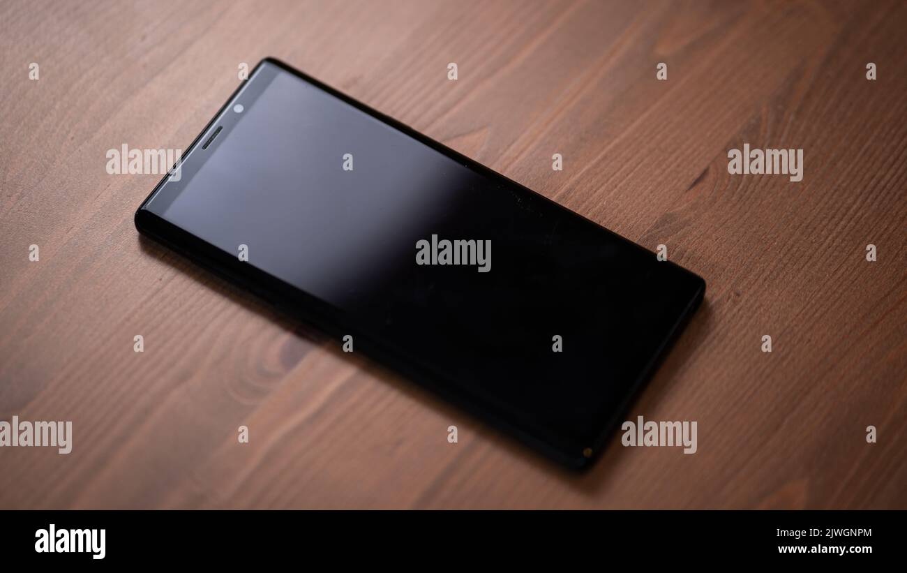 Schwarzes Smartphone geschlossen auf einem Holztisch sitzend Stockfoto