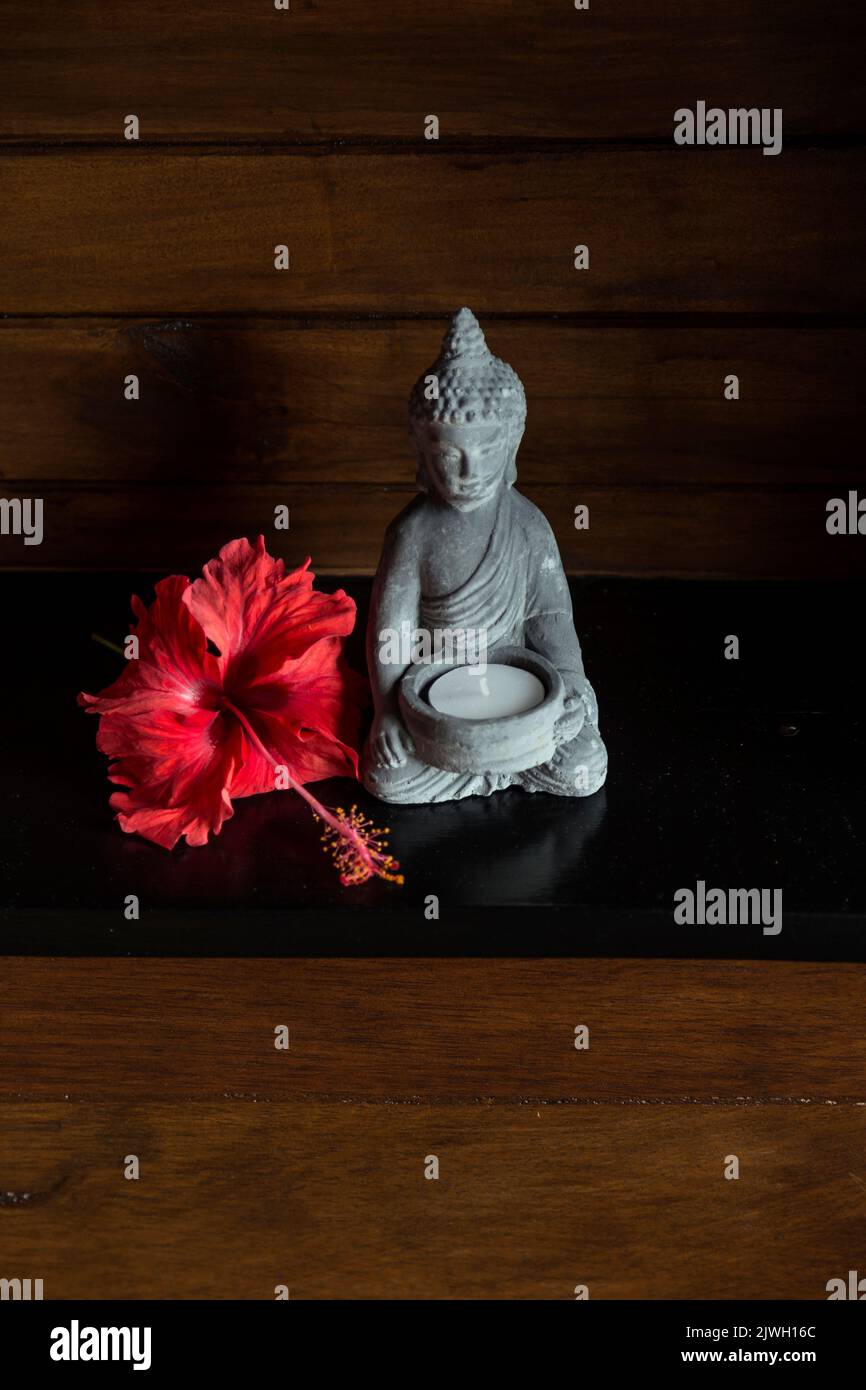 Kleine Buddha-Statue und eine rote Blume als Dekoration im Luxushotel. Urlaub Stockfoto