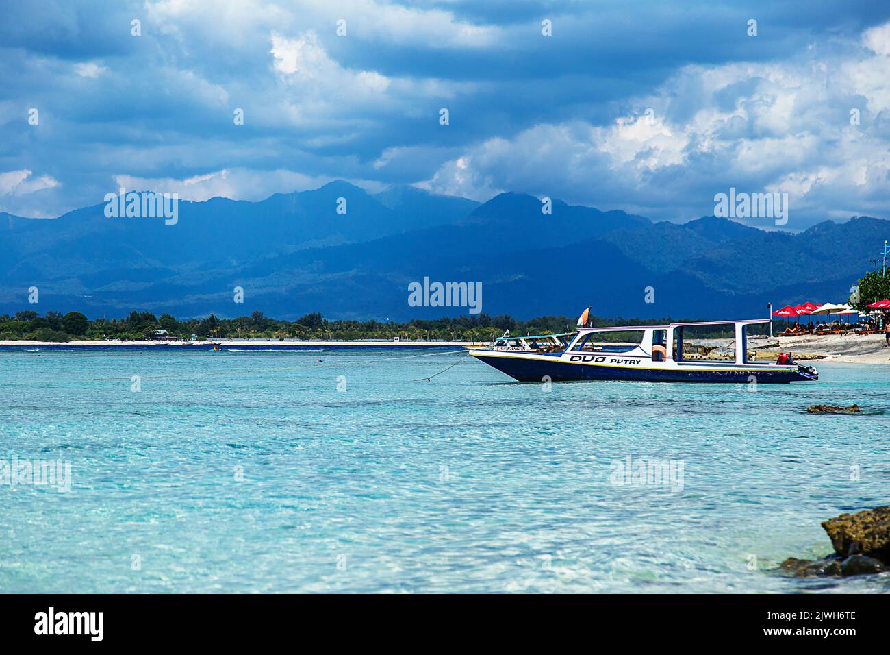 Bootstouren auf einem klaren und ruhigen türkisfarbenen Meer mit Wolken und Bergen im Hintergrund. Asiatisches Paradies Stockfoto