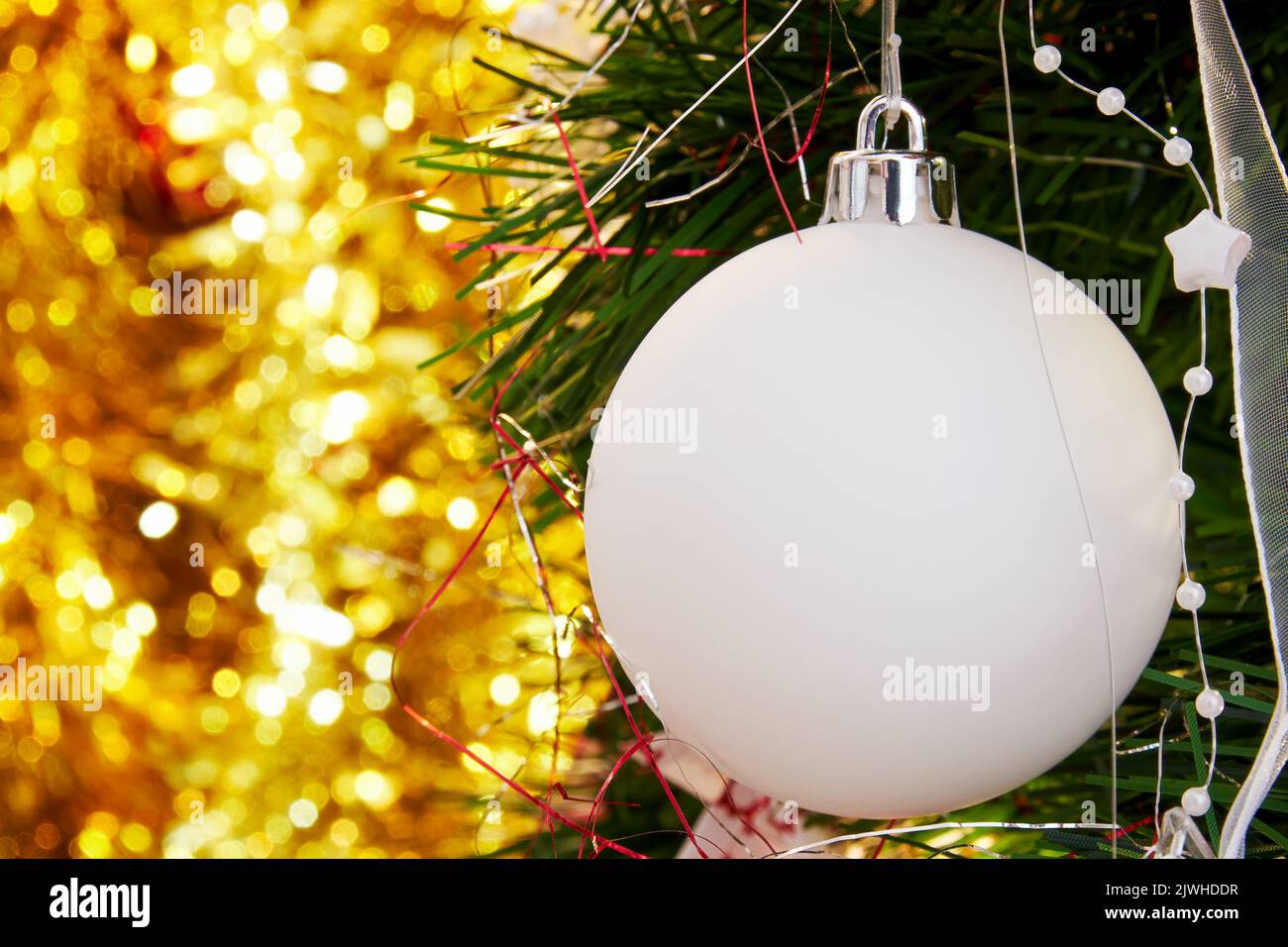 Weihnachtlicher immergrüner Baumzweig mit weißem Kugelspielzeug und goldenem verschwommenem Rücken. Banner-Vorlage für das neue Jahr mit Platz für Text Stockfoto