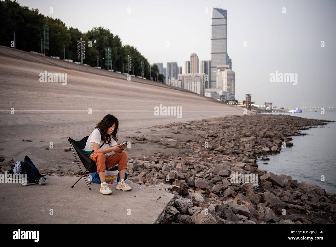 Wuhan, China. 05. September 2022. Eine Frau sitzt an den exponierten Ufern des Jangtse-Flusses. Eine Hitzewelle traf China im Sommer und beeinflussten die Nahrungsmittelproduktion, Fabriken, Stromversorgungen und den Transport erheblich. Die Hitzewelle hat auch den längsten Fluss Asiens, das Yangtse-Flussbecken, beeinflusst, was dazu führte, dass sein Wasserstand als der niedrigste seit Beginn der hydrologischen Aufzeichnungen im Jahr 1865 verzeichnet wurde. (Foto von Ren Yong/SOPA Images/Sipa USA) Quelle: SIPA USA/Alamy Live News Stockfoto