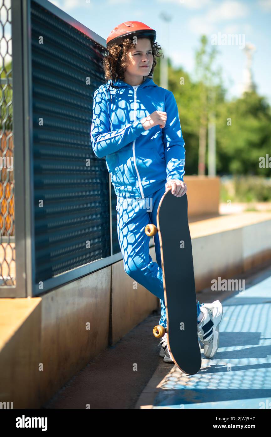 Nachdenklicher junger Skateboarder im Schutzhelm, der draußen steht Stockfoto