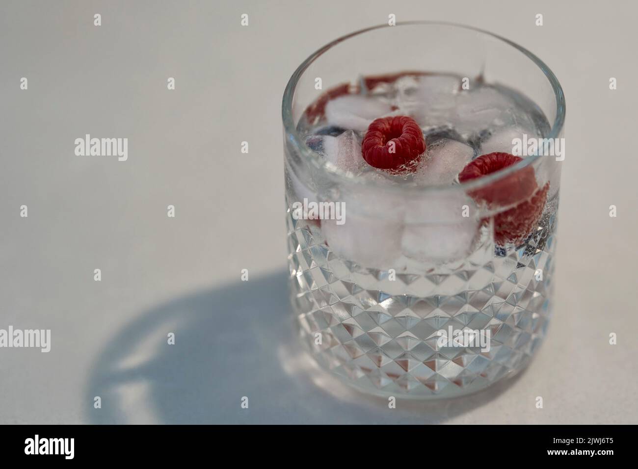 Gin und Tonic in doppeltem altmodischem Glas mit Eis und Himbeeren Stockfoto