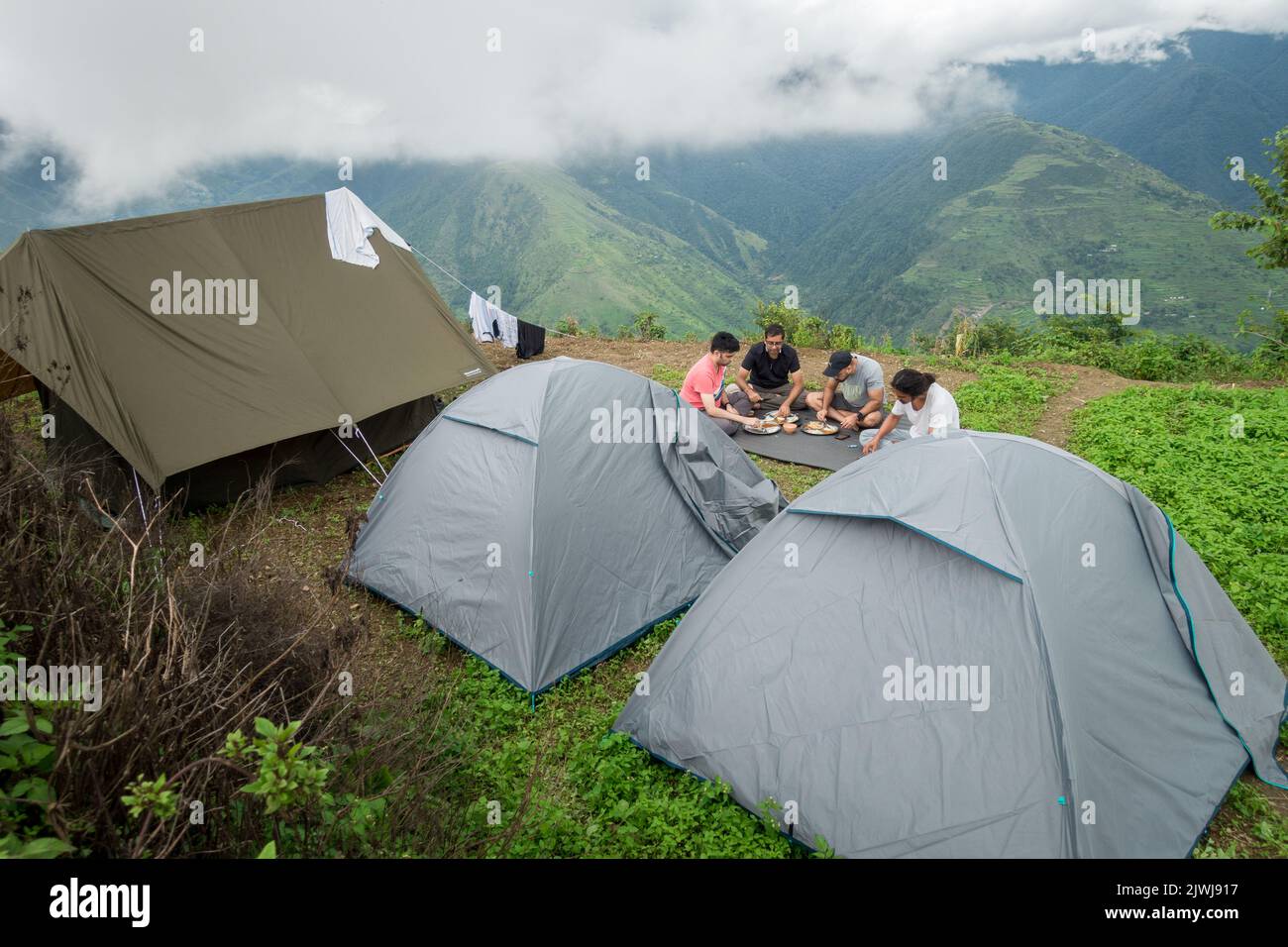 März 13. 2021 Nag Tibba Mountain, Uttarakhand Indien. Eine Gruppe von Camper und Wanderern genießen das Essen und spielen Gitarre auf dem Campingplatz. Stockfoto