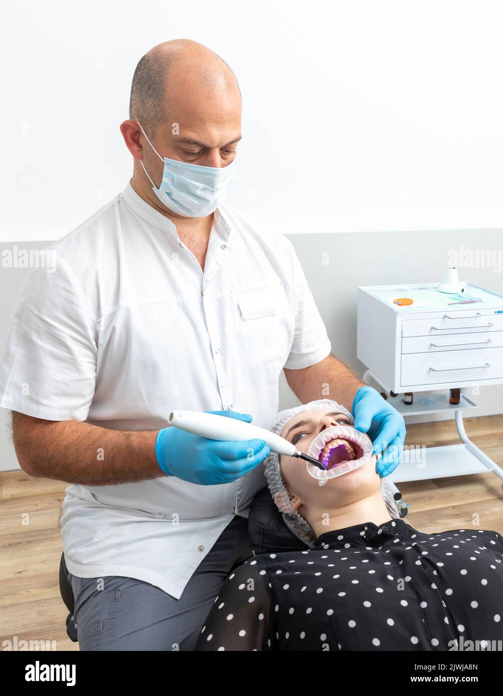 Zahnarzt mit Dental curing UV-Lampe auf die Zähne des Patienten Stockfoto