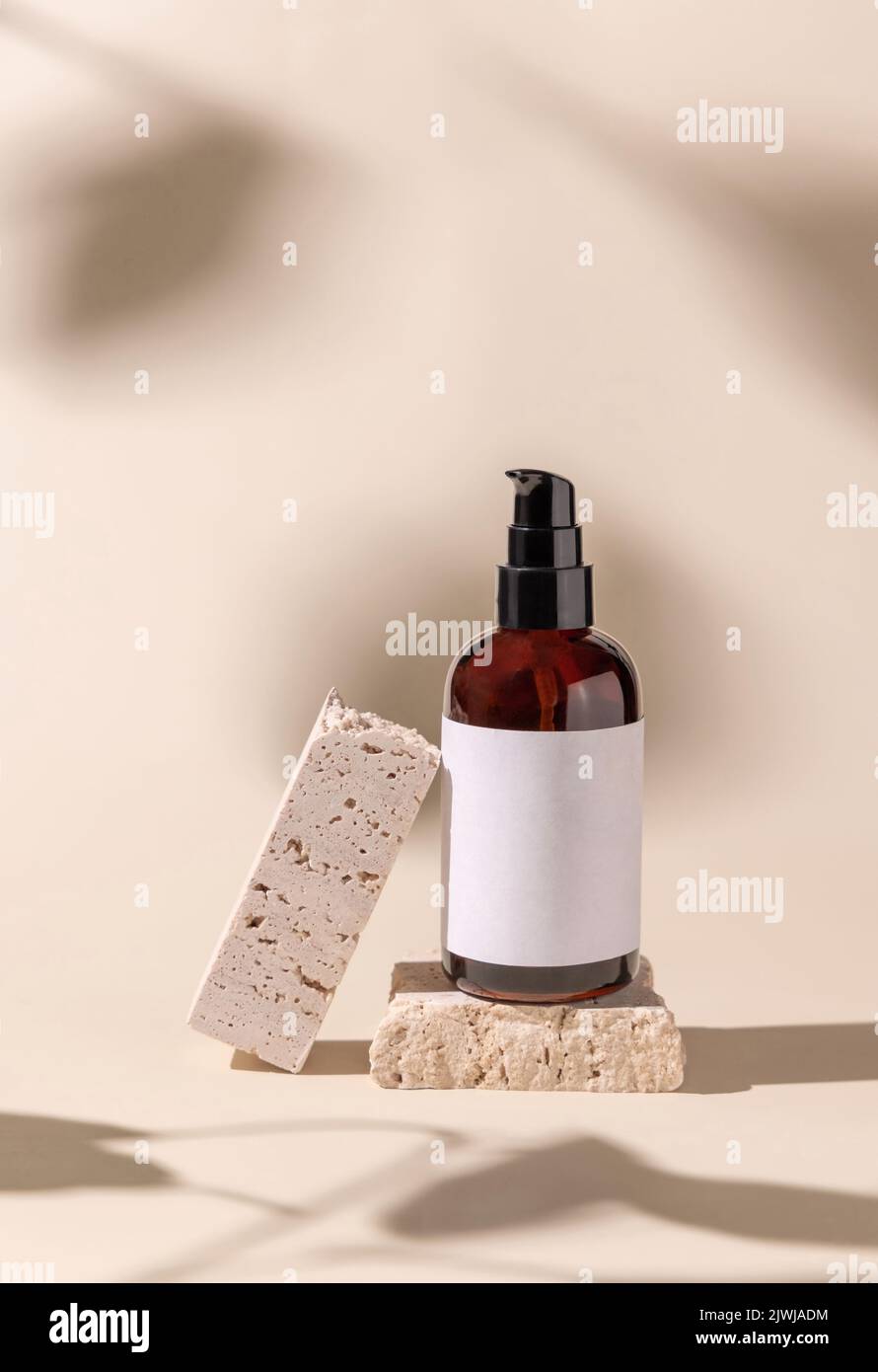 Brown Glass Cosmetic eine Pumpflasche auf Travertinstein auf hellbeige, harte Schatten, Nahaufnahme, Etikettenmockup. Hautpflegeprodukt, Lotion oder esse Stockfoto