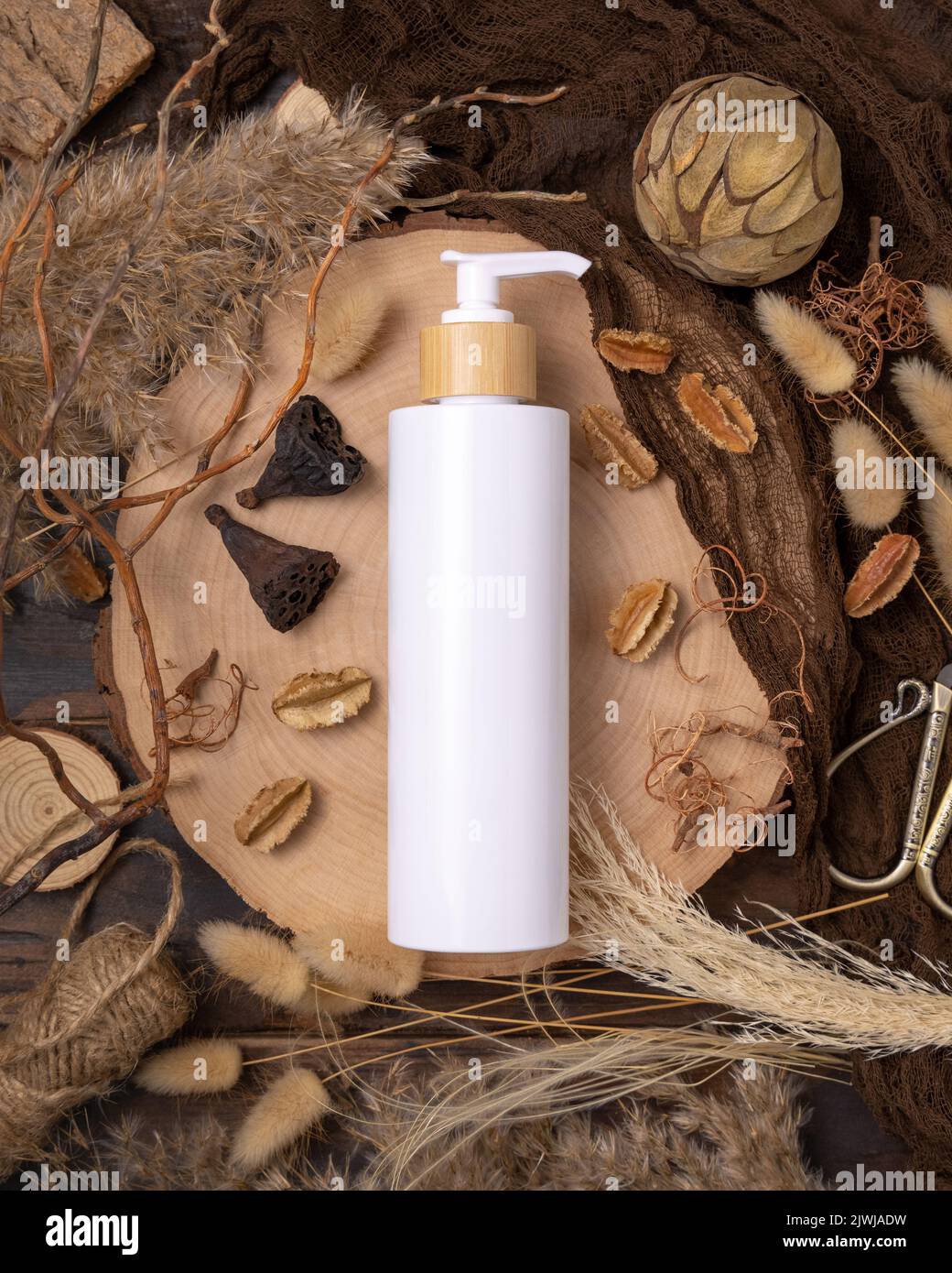 Nachfüllbare weiße eine Pumpflasche auf Holz in der Nähe von natürlichen Boho Dekorationen Draufsicht, Etikett Mockup. Hautpflegeprodukt, Lotion oder Essenz. Böhmische ec Stockfoto