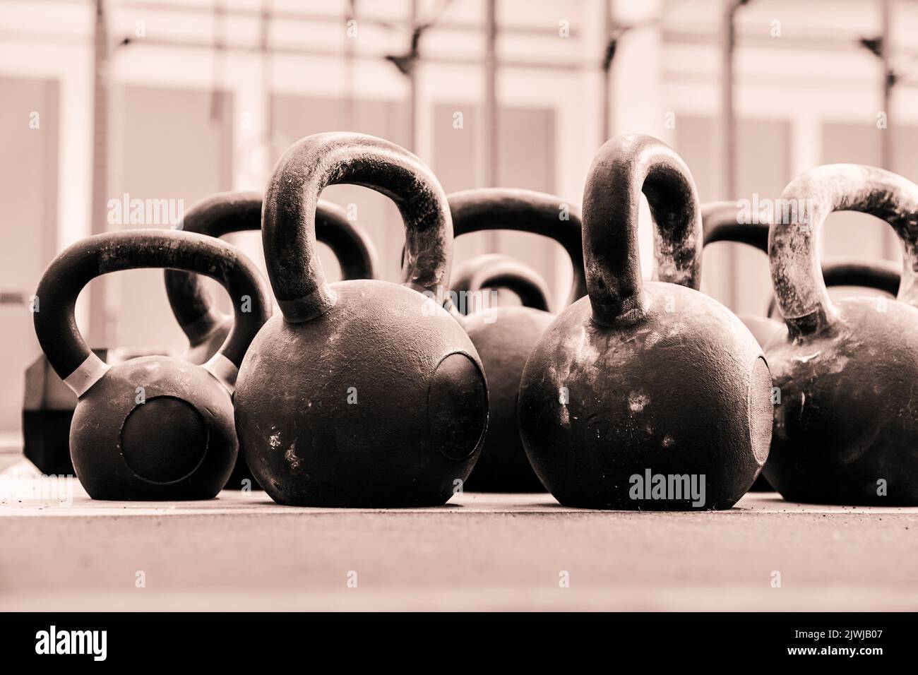 Im Erdgeschoss befinden sich viele schwere Kettlebells für funktionelles Training, die auf dem Boden in einem leichten Fitnessstudio platziert sind Stockfoto