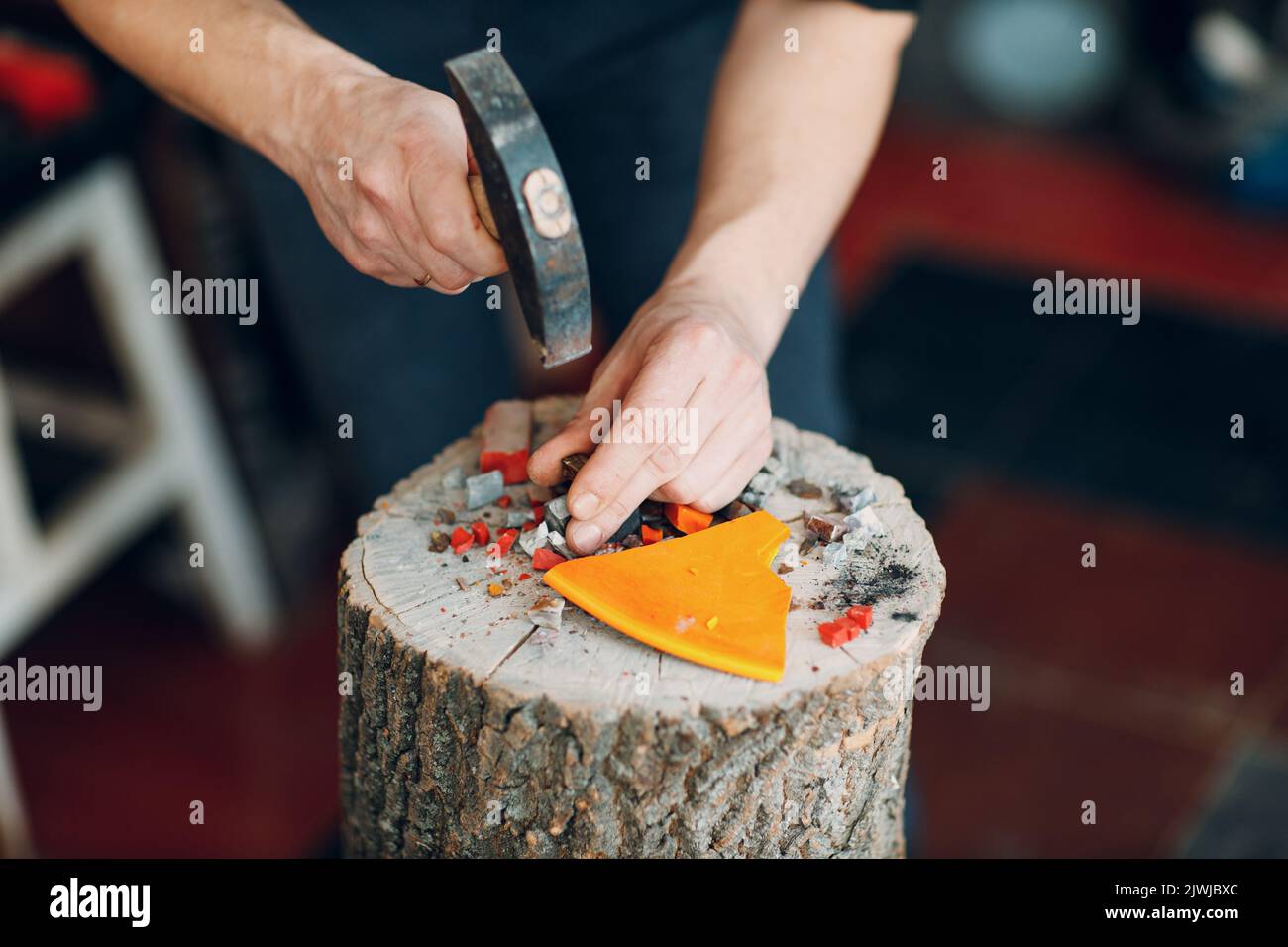 Handwerker schneidet zerbrechendes Smaltglas mit Hammer für Mosaikkunstwerke in der Werkstatt. Stockfoto