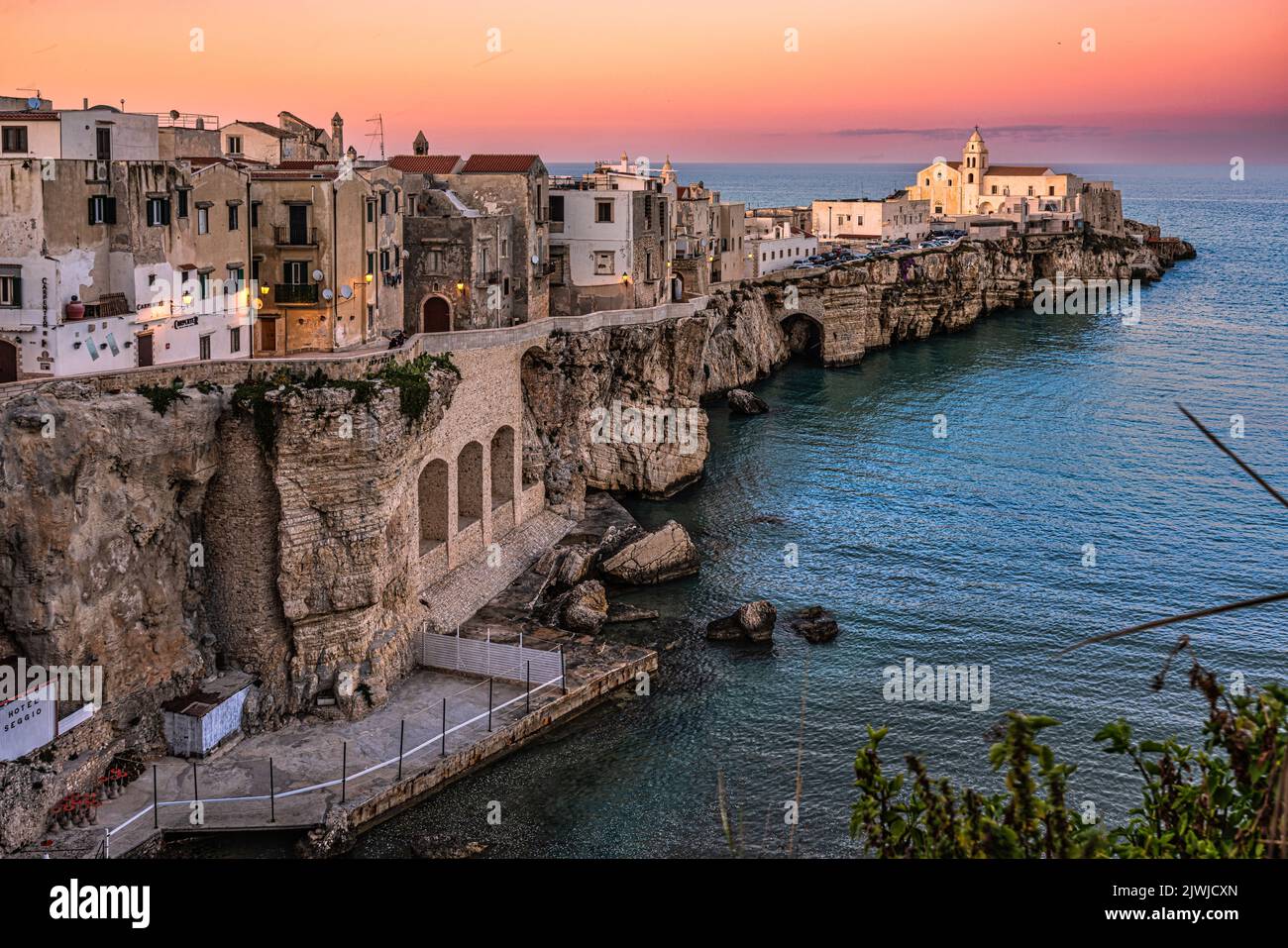 Blick auf den Sonnenuntergang von Punta San Francesco in Vieste. Die Kirche Retoria di San Francesco, die von den letzten Sonnenstrahlen erleuchtet ist. Vieste, Apulien Stockfoto