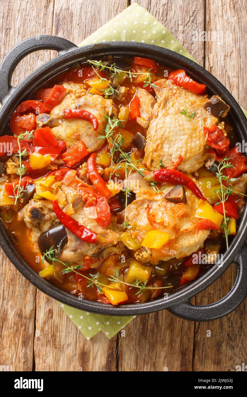 Kedjenou Chicken Ivory Coast Eintopf mit Gemüse in eigenem Saft in der Nähe in den Teller auf dem Tisch. Vertikale Draufsicht von oben Stockfoto