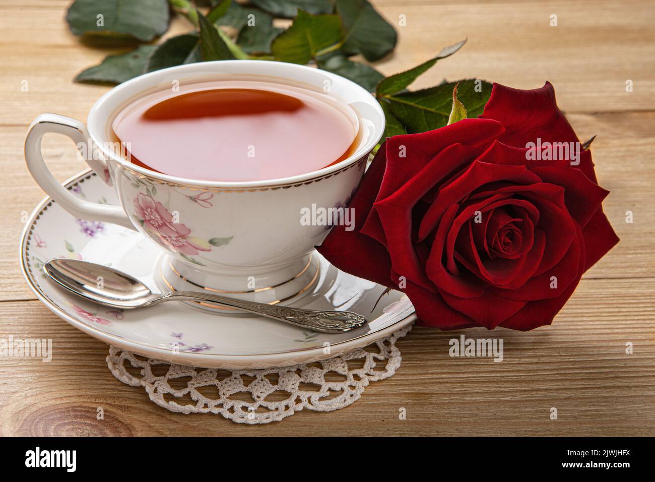 Frühstückskonzept. Eine Tasse Tee und eine rote Rose auf dem Tisch Stockfoto