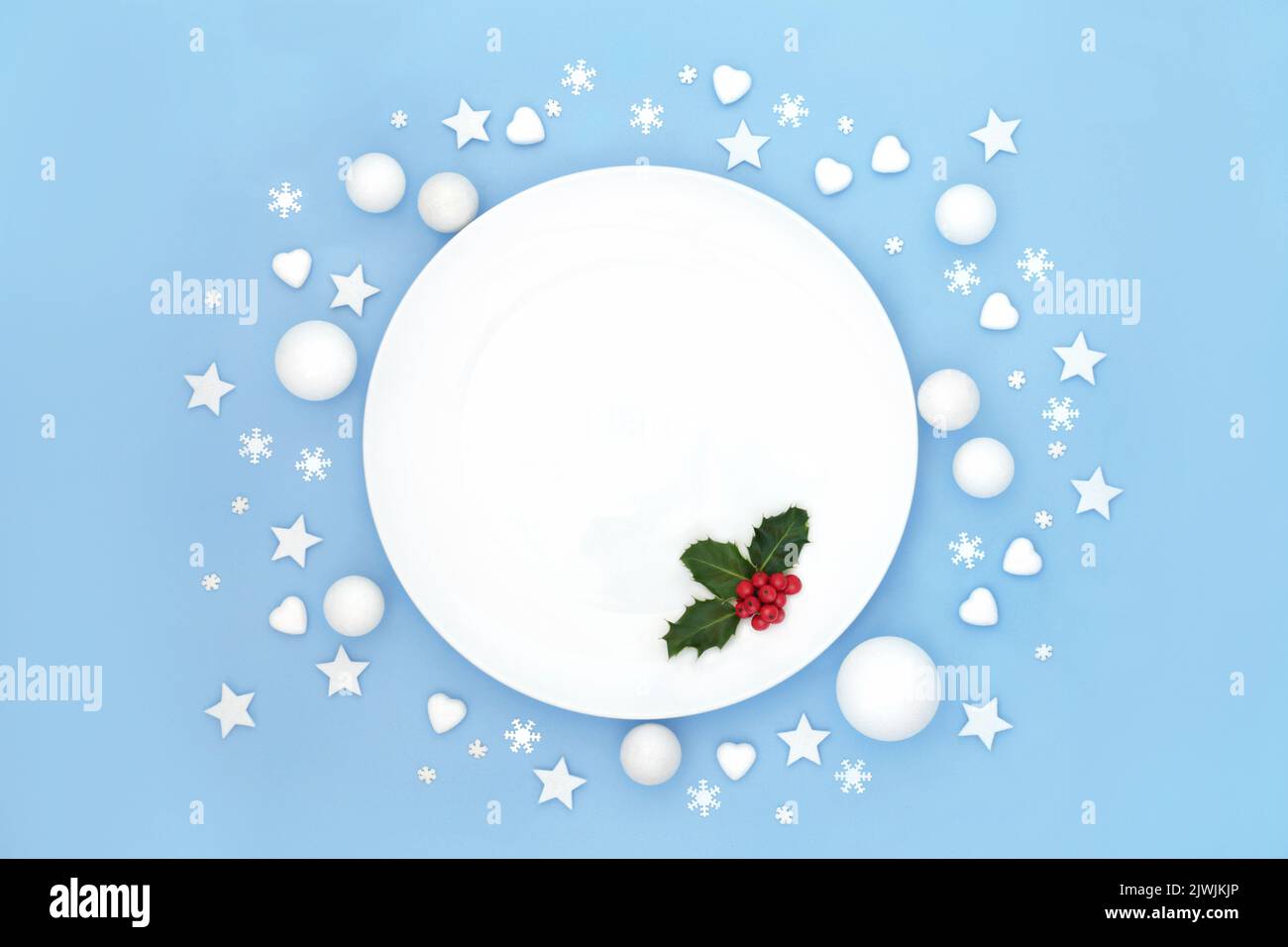 Weihnachtliche Essteller Tischdekor mit stacheligen roten Beeren und weiß mattierten Dekorationen. Abstraktes, minimalistisches Design für festliche Weihnachtsfeiertage Stockfoto