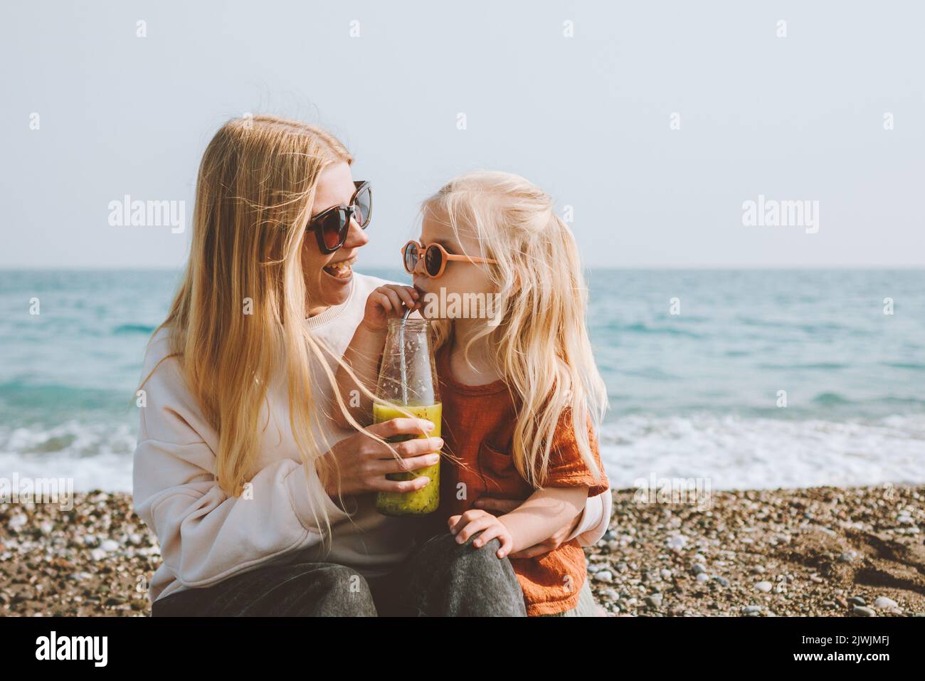 Familienurlaub Kind trinkt Smoothie mit der Mutter auf Strandreise im Freien gesund leben Mutter und Tochter zusammen zu Fuß Sommerausflug Stockfoto