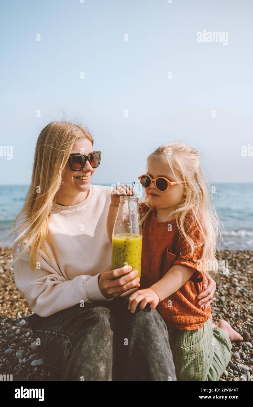 Mutter und Kind trinken Smoothie Outdoor Sommerferien Familie auf Strandreise gesunder Lebensstil vegan organic beverage fresh fruit Juice Stockfoto