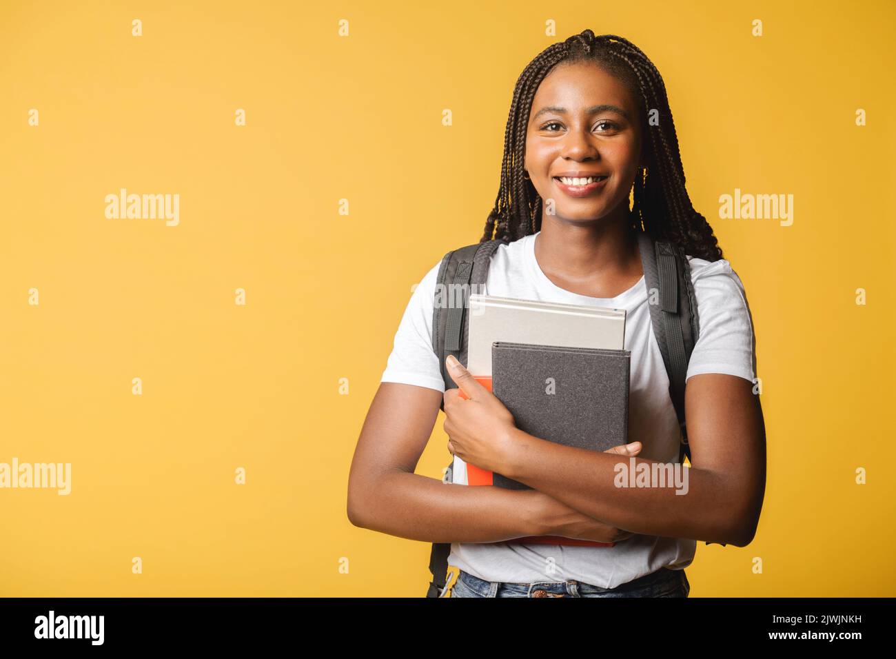 Glücklich aufgeregt Studentin mit Rucksack isoliert auf gelb stehen und hält Bücher und Abstracts, bereit zum Studium, zurück zur Schule Konzept Stockfoto