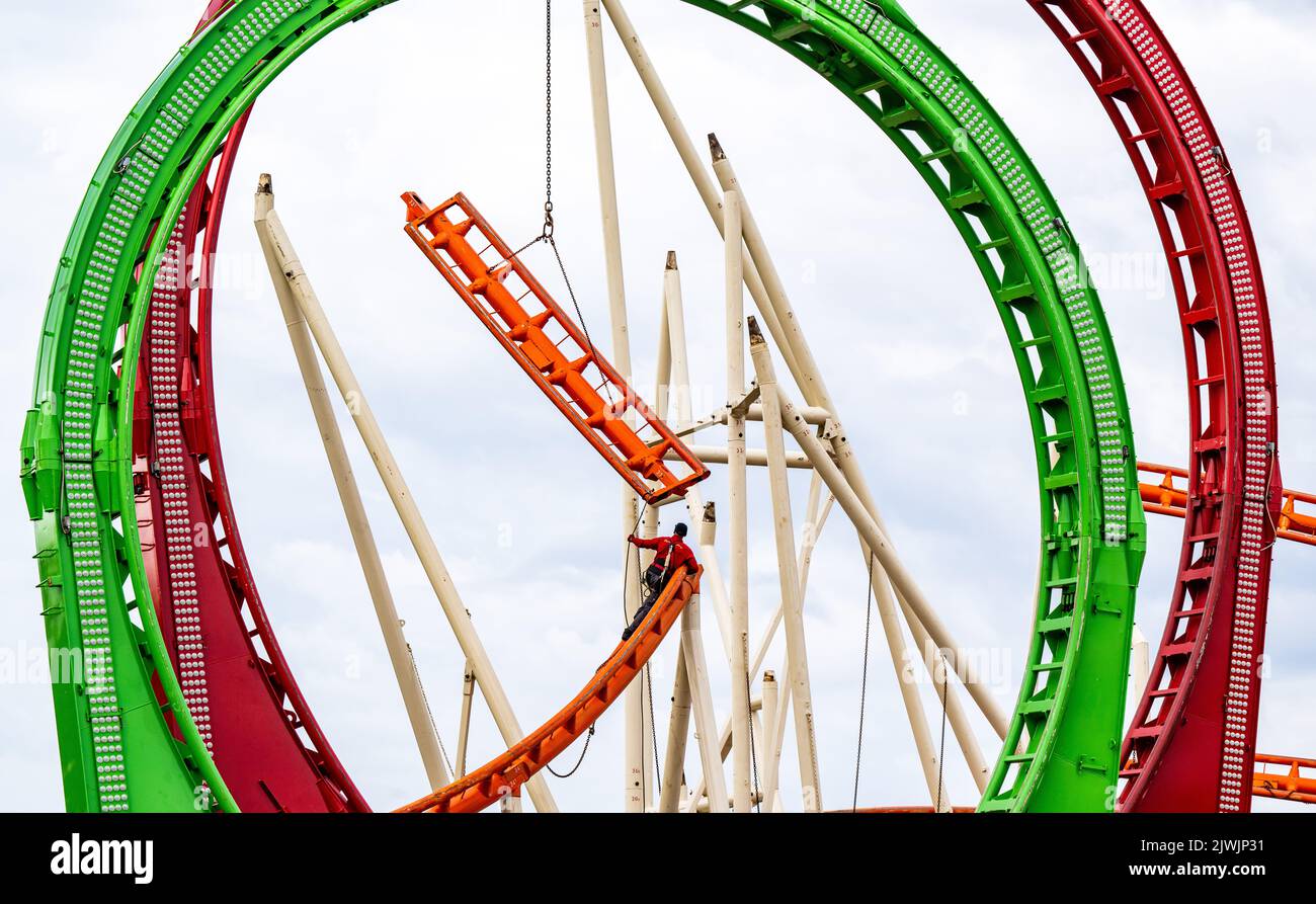 München, Deutschland. 06. September 2022. Ein Arbeiter montiert auf dem Wiesn-Gelände bunte Gleisteile einer großen Achterbahn, deren Spezialität die fünffache Schleife ist. Das Oktoberfest findet in diesem Jahr von 17.09.2022 bis 03.10.2022 statt. Kredit: Peter Kneffel/dpa/Alamy Live Nachrichten Stockfoto