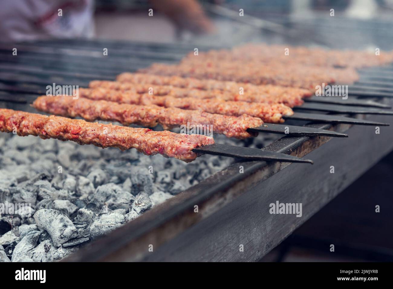 Traditionelle köstliche Adana Kebab auf einem Grill mit Rauch, Nahaufnahme Stockfoto