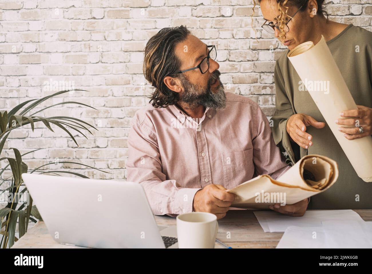 Mitarbeiter, die am Schreibtisch im Büro mit Papierkarten und einem Laptop zusammenarbeiten. Konzept der Zusammenarbeit von Mann und Frau in der Teamkooperat Stockfoto