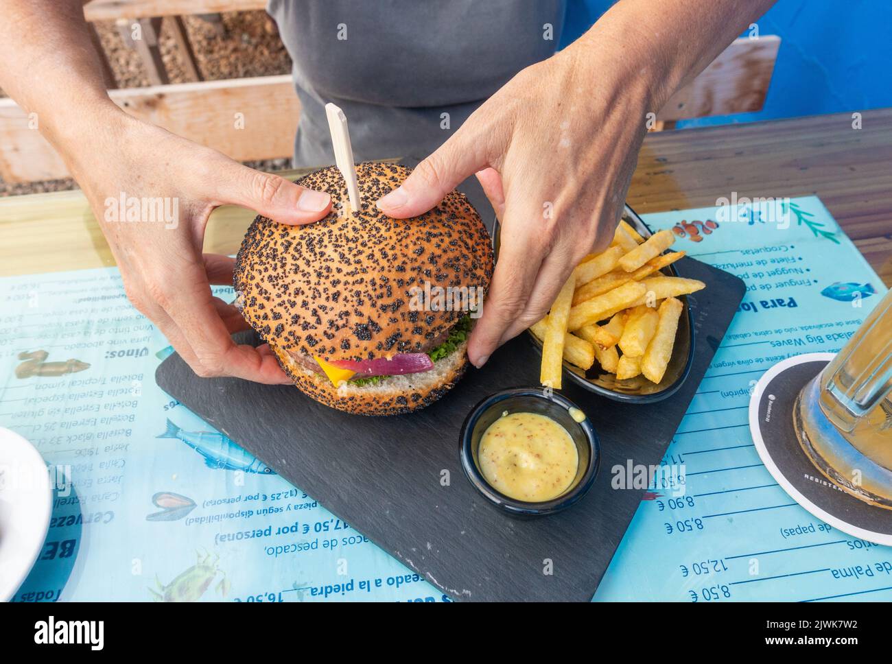 Frau, die in der spanischen Bar Hamburger und Pommes isst Stockfoto