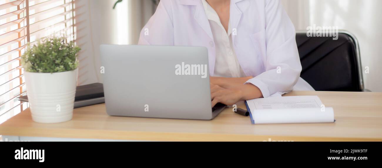 Junge Ärztin mit Laptop-Computer und suchen Dokument Papier über Patienten für die Diagnose in der Klinik, Ärztin weibliche Arbeit und Lesen Docum Stockfoto