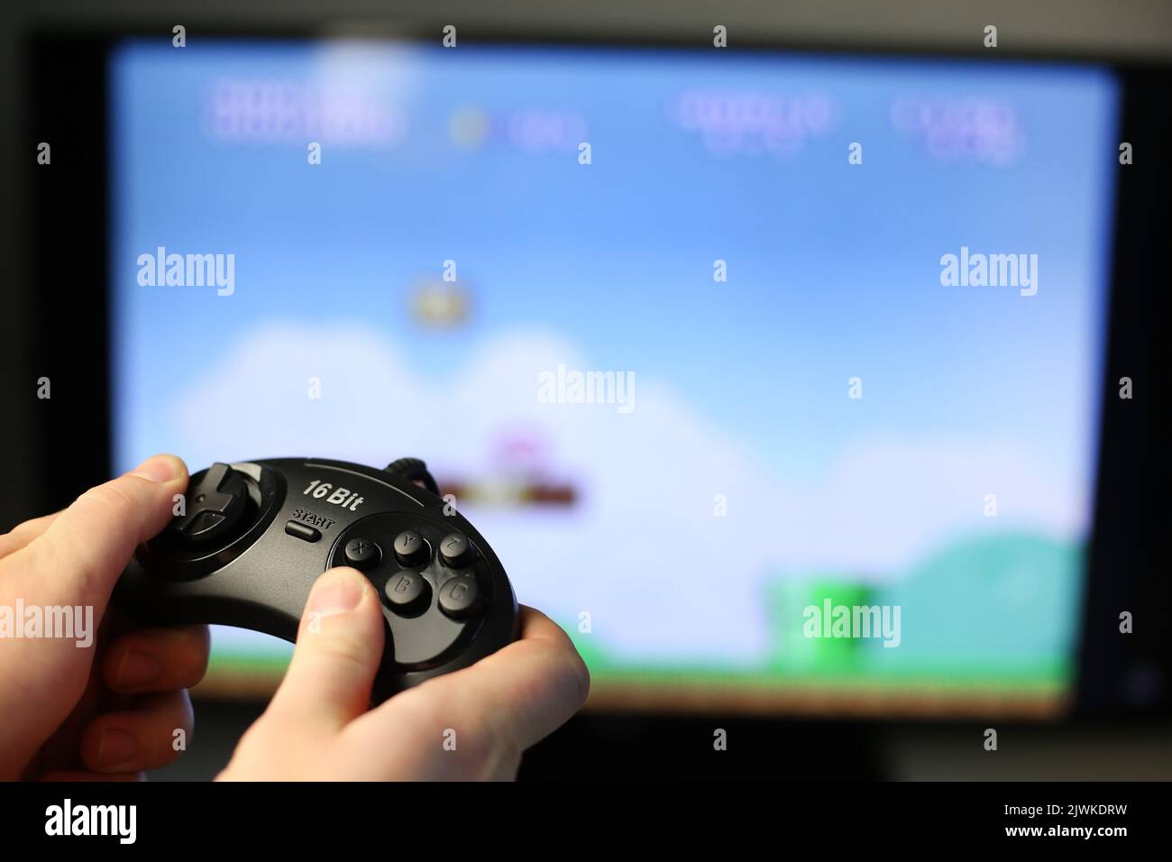 Spielt ein Retro-Spiel auf dem Fernseher, während der klassische schwarze Joystick gedrückt wird Stockfoto