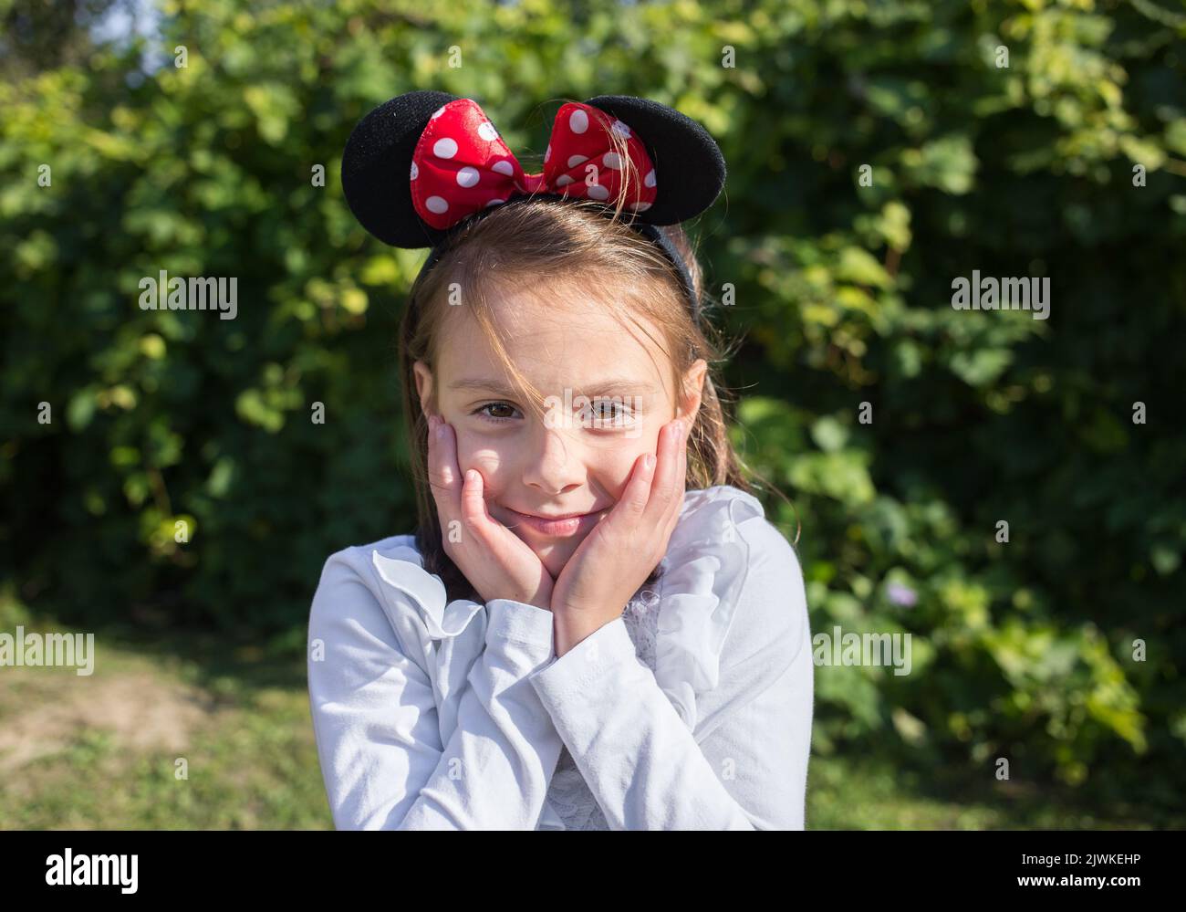 Schönes Mädchen 6-7 Jahre alt mit Mausohren auf dem Kopf. Festliche Stimmung, Geburtstag, positive, fröhliche Kindheit Stockfoto