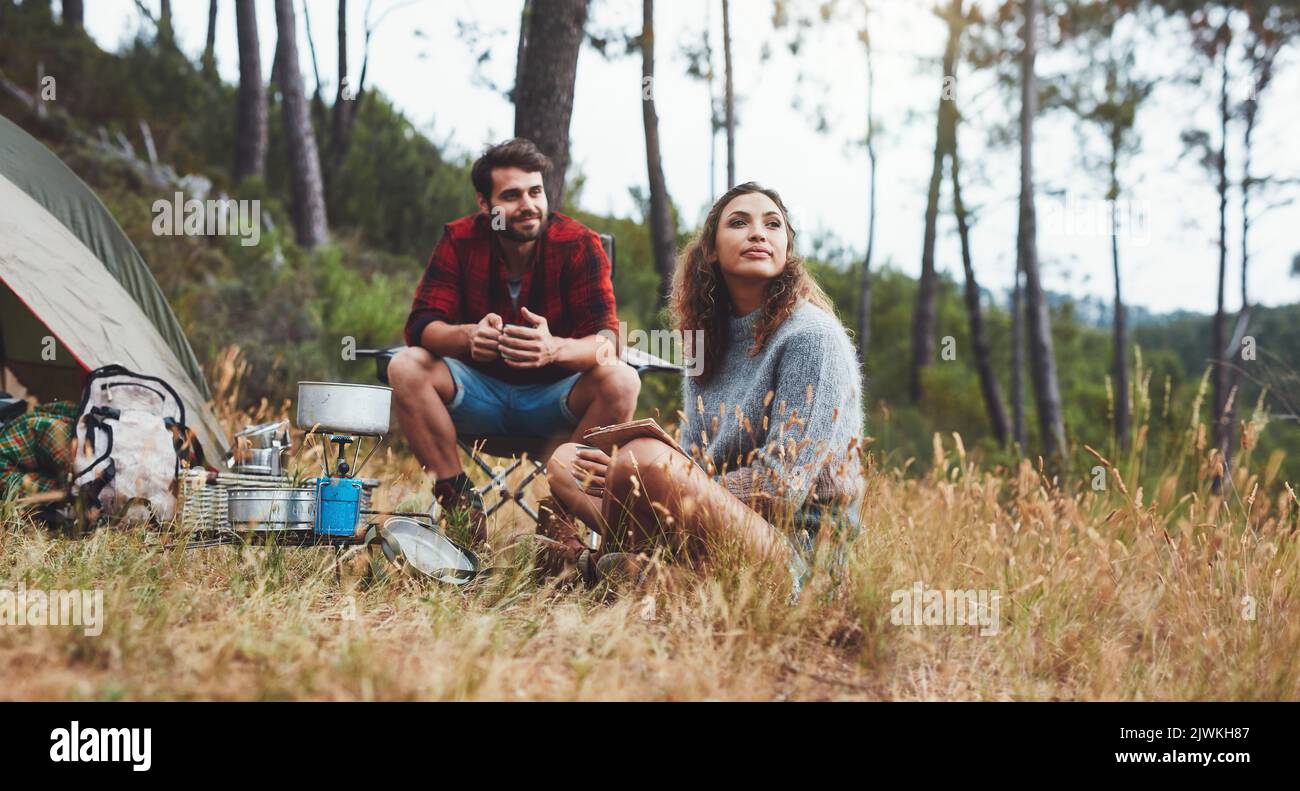 Sorgloses junges Paar, das auf ihrem Campingplatz sitzt. Junger Mann und Frau, die im Freien in der Natur campen. Stockfoto