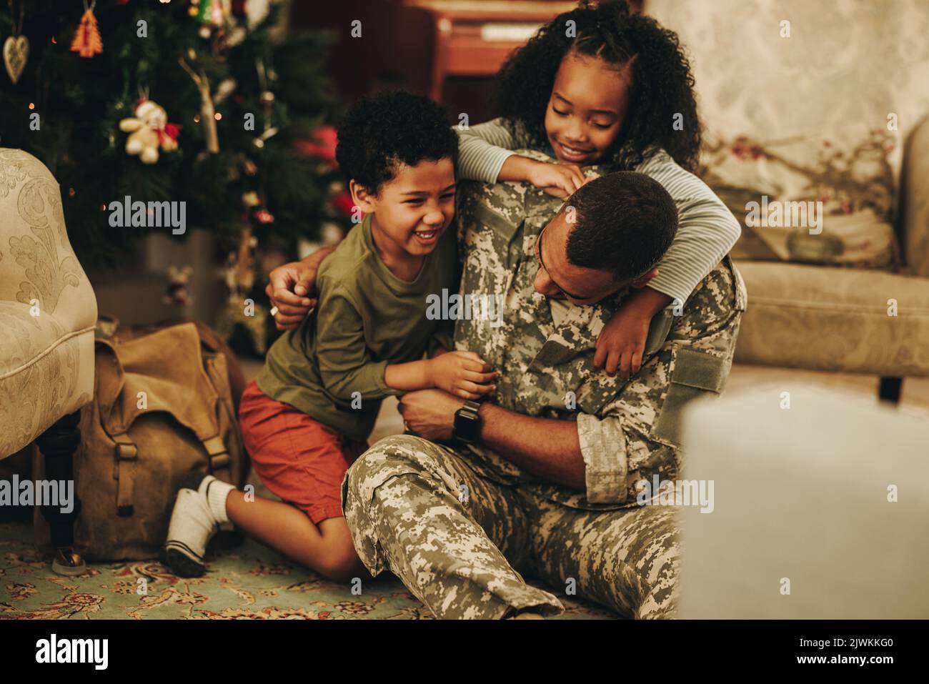 Armeesoldat, der zu Weihnachten mit seinen Kindern spielt. Glücklicher Militärvater, der sich zu Hause mit seinen Kindern wiedervereinigt. Soldat verbringt gute Zeit mit seinem fa Stockfoto