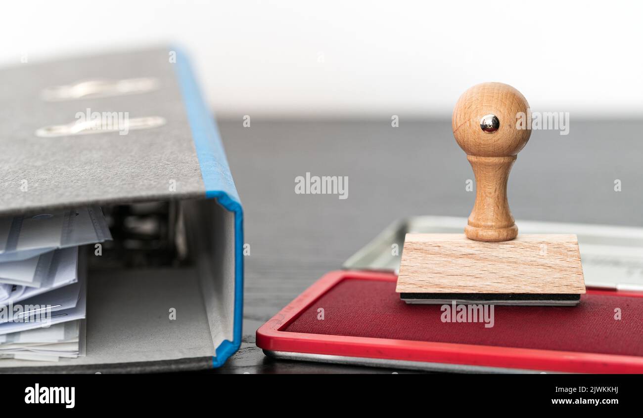 Rechteckiger Gummistempel auf Tintenpad auf Holztisch mit Aktenordner Stockfoto