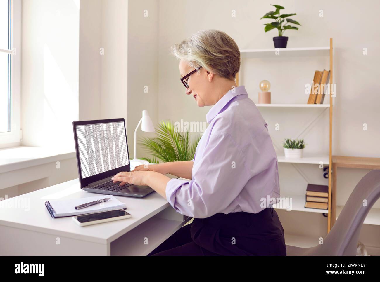 Erfahrene Geschäftsfrau, die im Büro Konten führt und mit Kalkulationstabellen arbeitet. Stockfoto