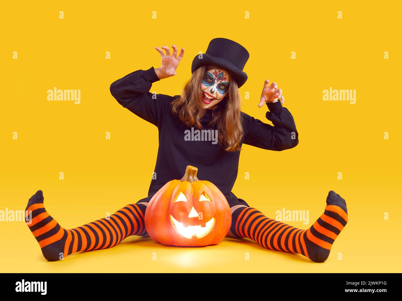 Fröhliches Mädchen mit Halloween Make-up macht Kratzen Geste auf orangefarbenem Hintergrund. Stockfoto