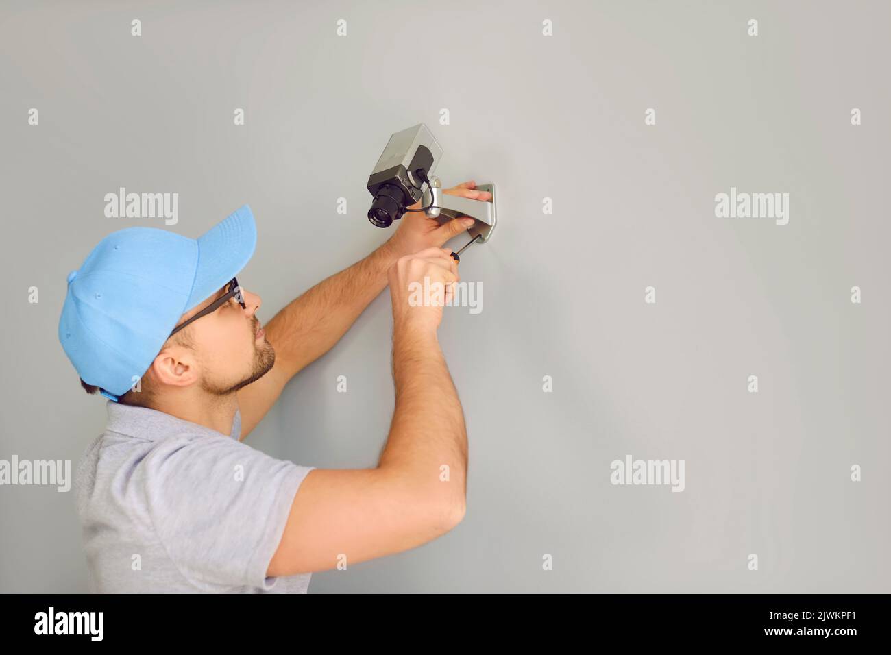 Der Sicherheitsspezialist des Unternehmens, man, montiert Überwachungskameras für das CCTV-System an der Wand im Gebäude Stockfoto