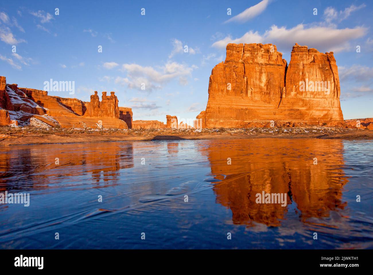 Die Orgel in den Courthouse Towers spiegelt sich in einem kurzlebigen gefrorenen Schneeschmelzloch im Arches National Park, Moab, Utah. Stockfoto