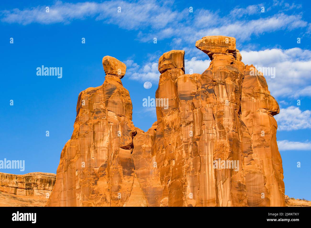 Der Mond über den drei Klatsch- und Hoodoos im Abschnitt Courthouse Towers des Arches National Park, Moab, Utah. Stockfoto