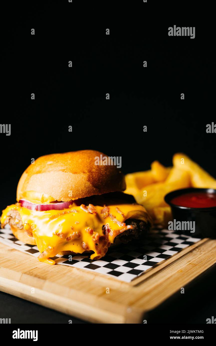 Doble Burger mit geschmolzenem Käse und gekrönt mit Speck auf schwarzem Hintergrund Stockfoto